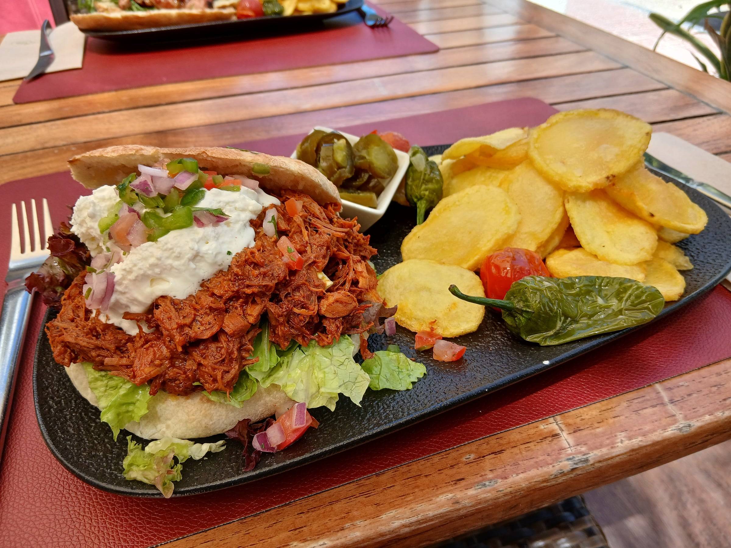 Pita de carne desmenuzada con salsa de yogur, patatas fritas y pimientos