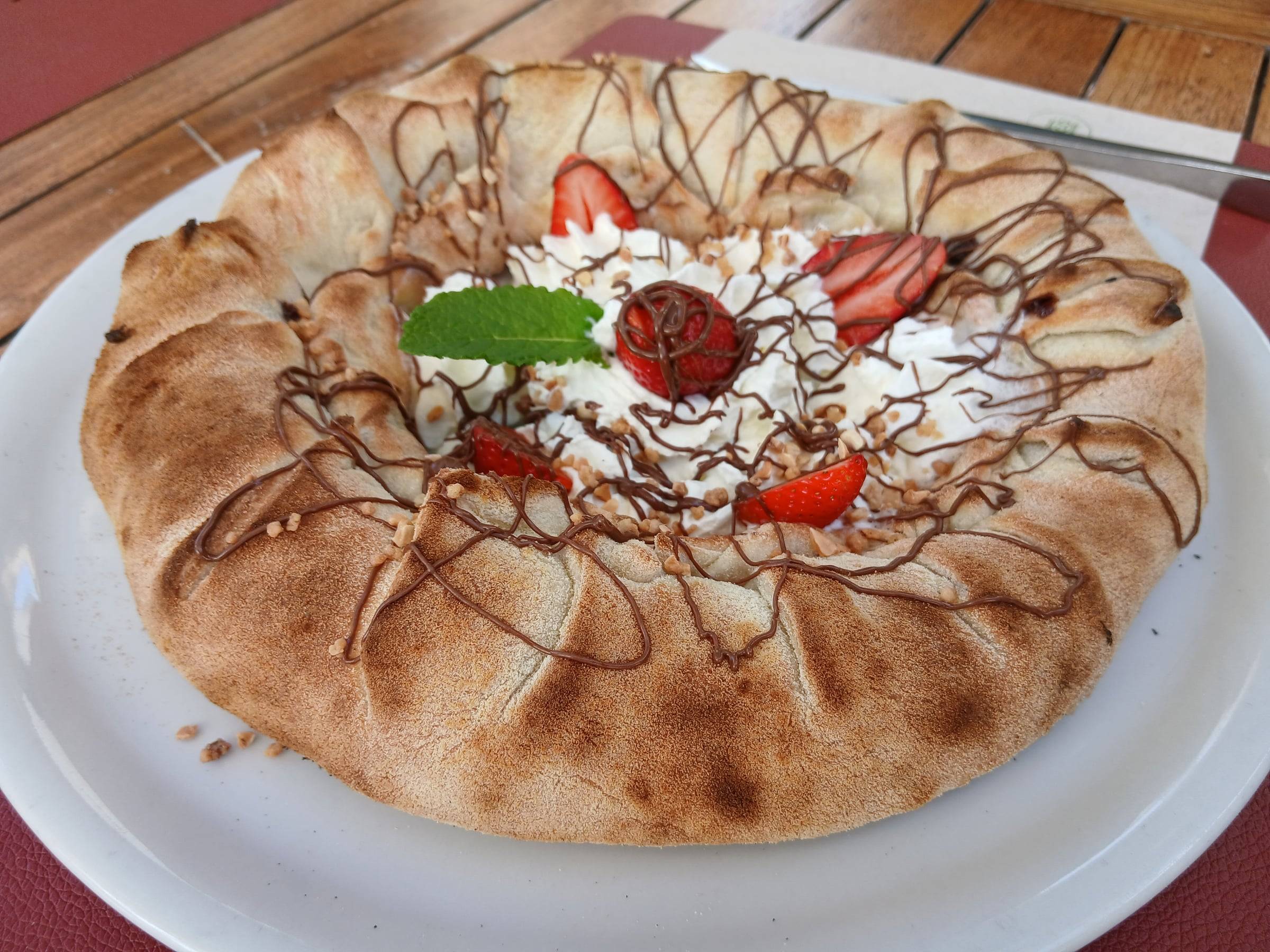 Pizza dulce con chocolate, nata, fresas y avellanas